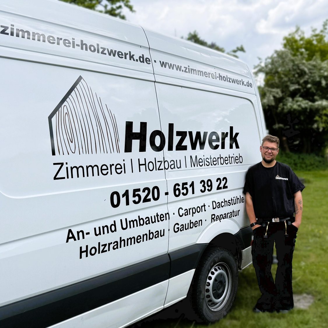 Ein Handwerker steht neben einem weißen Lieferwagen mit der Aufschrift „Holzwerk“.